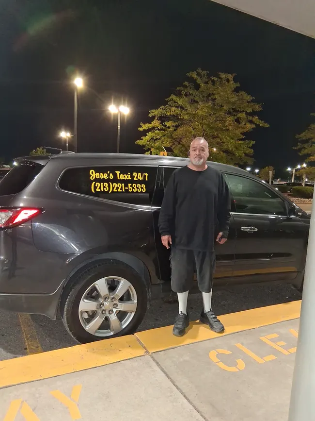 Jose standing beside his branded taxi